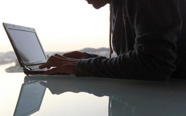 Una persona, manejando un ordenador desde el que realizar trámites municipales.