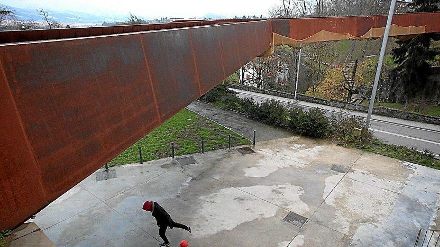 Un niño juega con una pelota junto al frontón debajo la pasarela del Labrit, donde se observa la presencia de una malla colocada para evitar desprendimientos.