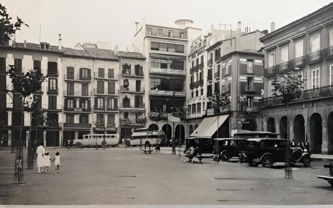 Postal de 1935. Esquina sudeste de la plaza. Desde la izquierda, puede verse el n&uacute;mero 12 y a continuaci&oacute;n las casas con n&uacute;meros 13 y 14 que fueron derribadas para construir el nuevo edificio de Huarte y Compa&ntilde;&iacute;a; en la