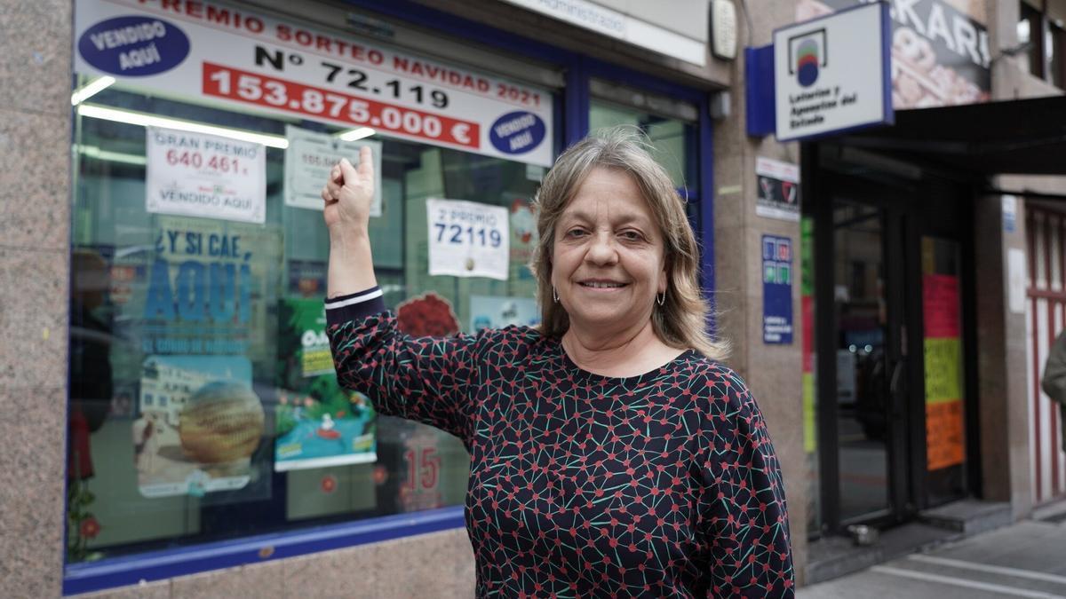 María José Berzosa delante de su despacho de lotería con el número agraciado el pasado sorteo de Navidad con el segundo premio