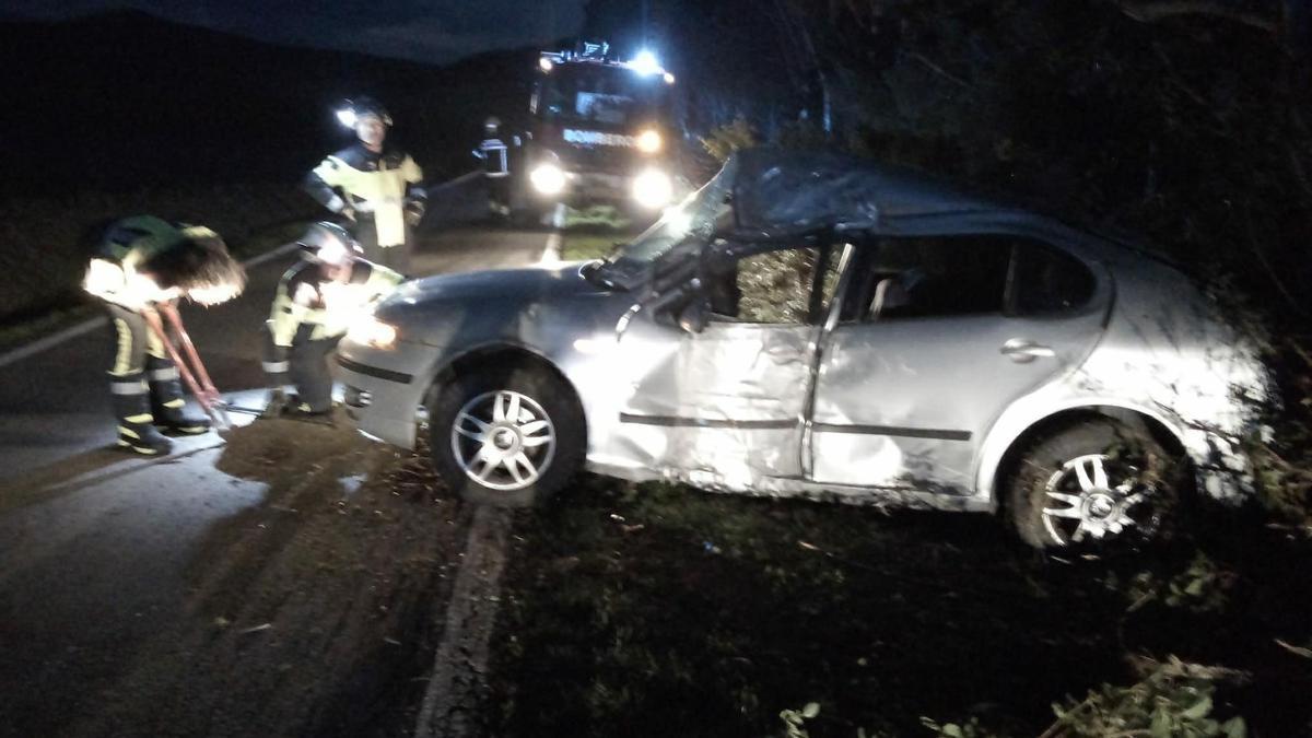 Bomberos junto al coche accidentado.