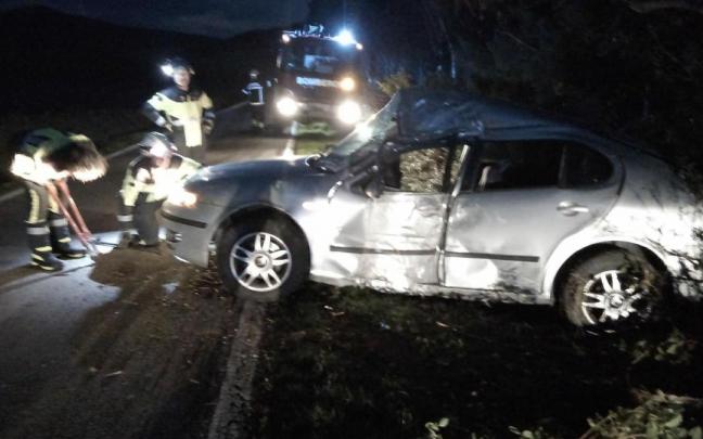 Bomberos junto al coche accidentado.