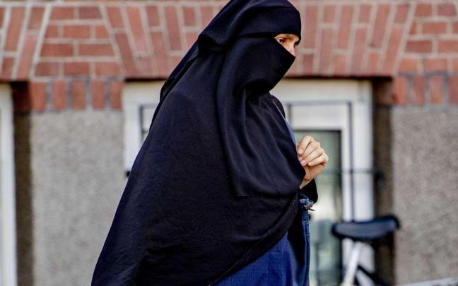 Una mujer pasea con un velo niqab. Una mujer pasea con un velo niqab.