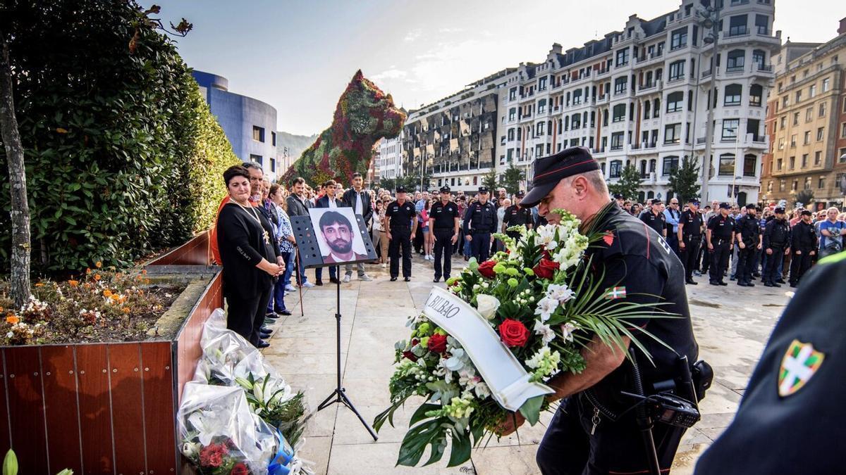 Agentes de la Ertzaintza ponen flores delante del monolito que hay en recuerdo de Txema Agirre, ante la mirada de su viuda, durante el 20 aniversario del asesinato.