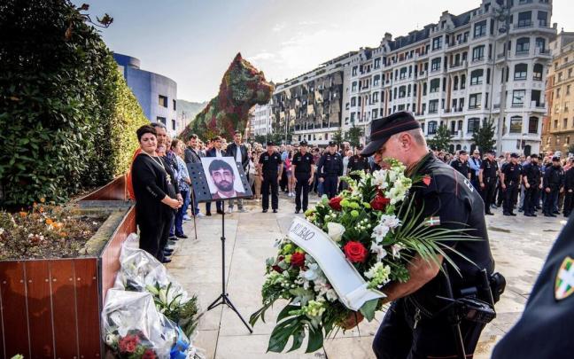 Agentes de la Ertzaintza ponen flores delante del monolito que hay en recuerdo de Txema Agirre, ante la mirada de su viuda, durante el 20 aniversario del asesinato.