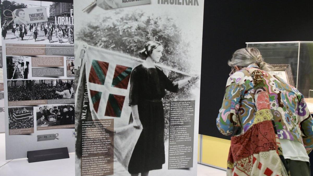 Una mujer observa uno de los 24 paneles informativos de la exposición 'EAB 100 urte. Emakumeak Aberria eginez'