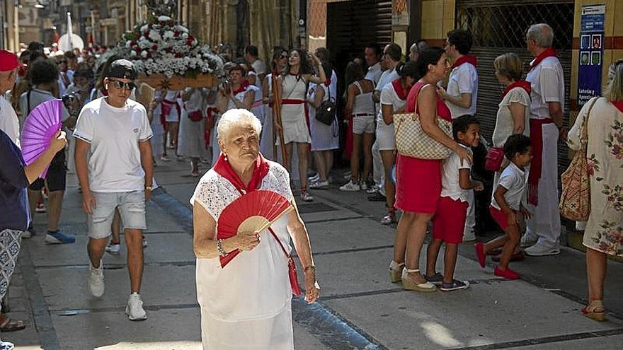 Una señora precede la procesión en la calle Mayor con el abanico.