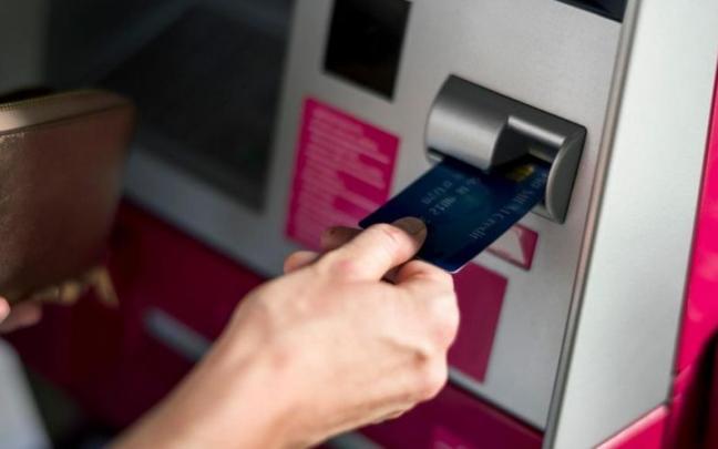 Una persona realiza una operación con su tarjeta en un cajero automático. Una persona realiza una operación con su tarjeta en un cajero automático.