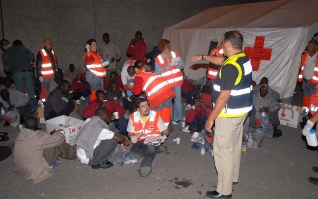 Miembros de la cruz roja y la guardia civil, asisten a cincuenta y siete inmigrantes que llegaban a la costa española, dos de ellos menores de edad. Miembros de la cruz roja y la guardia civil, asisten a cincuenta y siete inmigrantes que llegaban a la costa española, dos de ellos menores de edad.