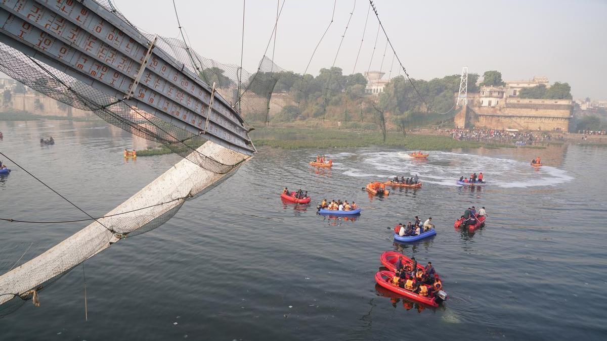 Los servicios de rescate junto a los restos del puente derrumbado en Morbi.