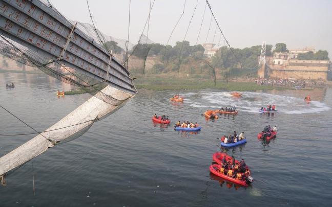 Los servicios de rescate junto a los restos del puente derrumbado en Morbi.
