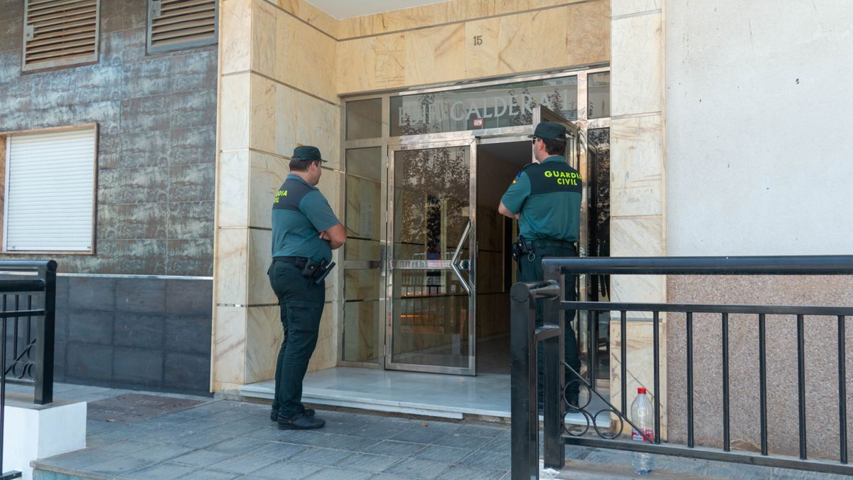 Dos agentes vigilan la entrada de la casa en la que una mujer de 50 años apareció muerta en Granada.