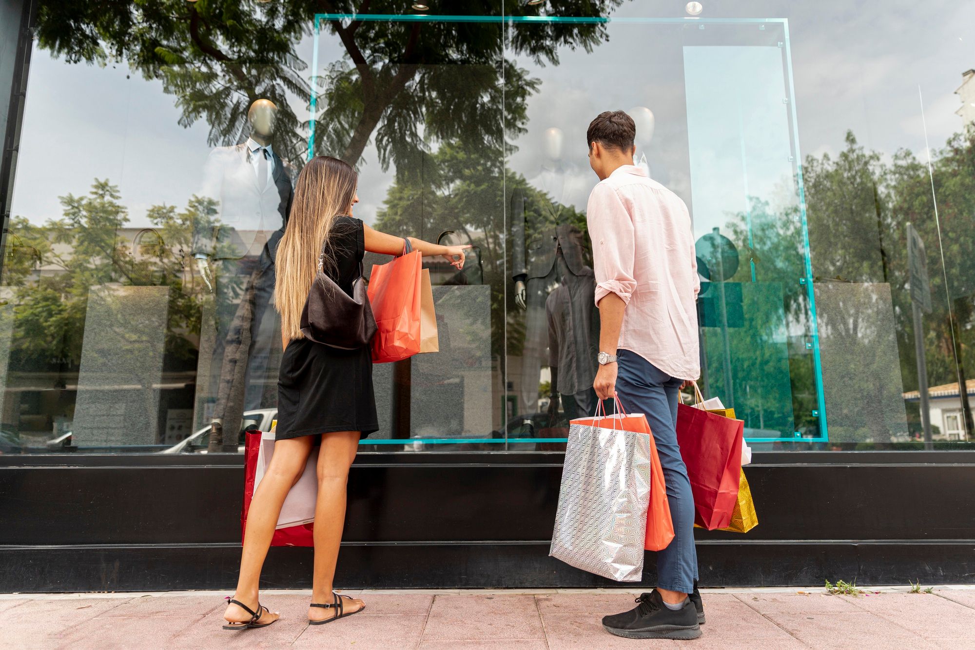 Una pareja cargada de bolsas observa un escaparate.