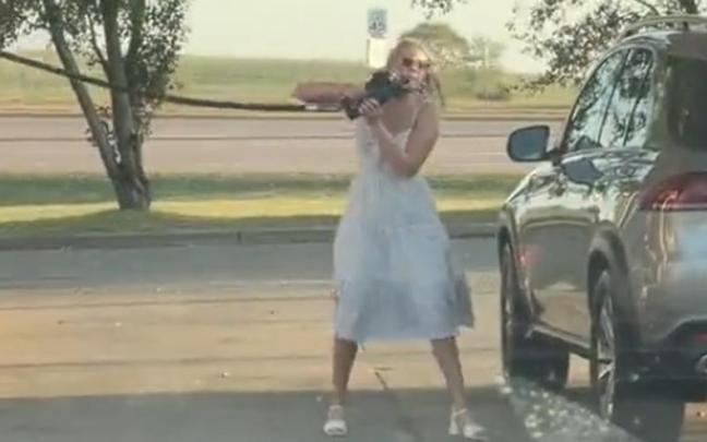 La joven, intentando llegar con la manguera a su coche, aunque el depósito de gasolina está al otro lado.