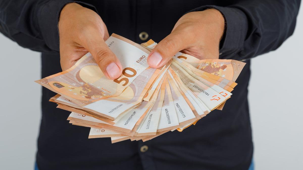 Un hombre muestra un fajo de billetes en su domicilio.