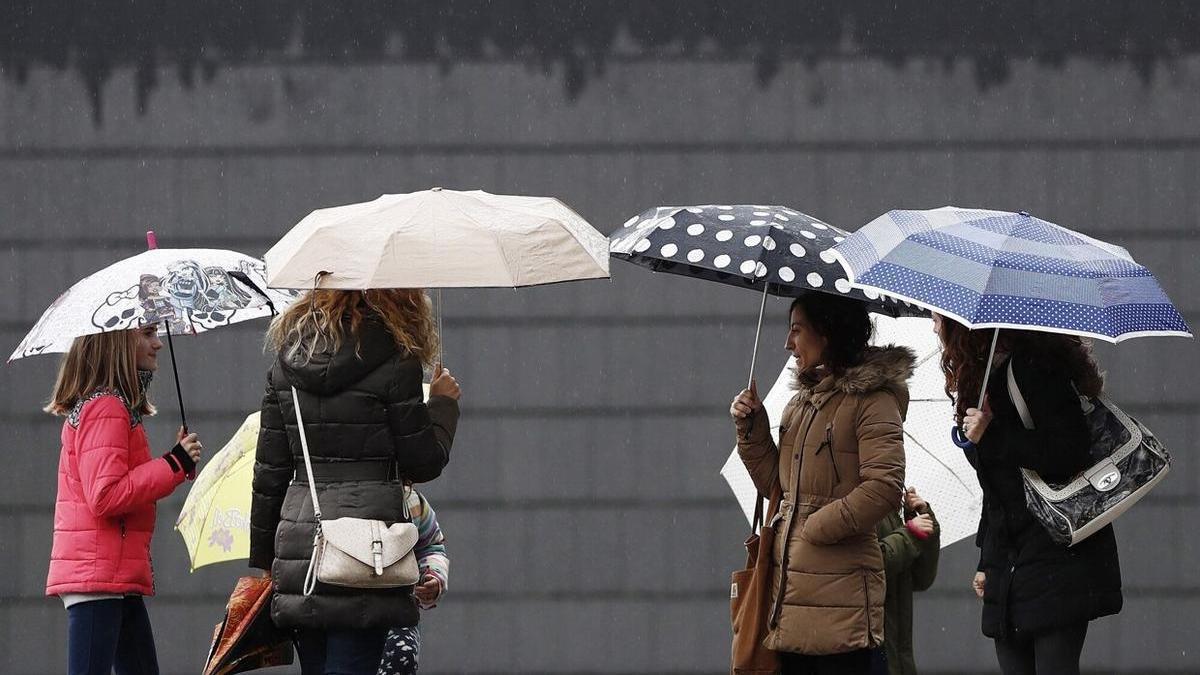 Un grupo de personas se protege con paraguas de la lluvia