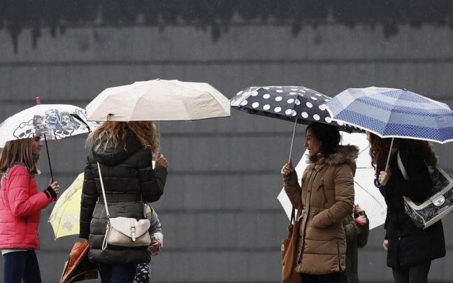 Un grupo de personas se protege con paraguas de la lluvia Un grupo de personas se protege con paraguas de la lluvia