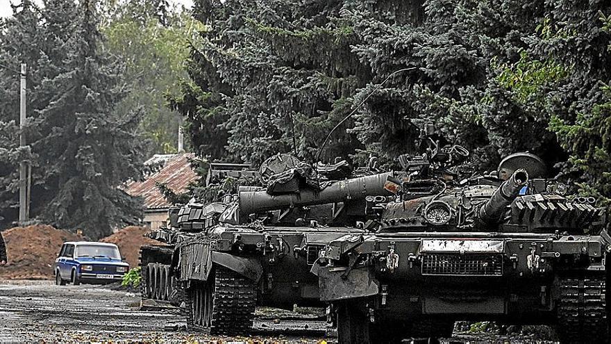 Un civil camina junto a tanques abandonados por las tropas rusas en su huida ante el avance de las fuerzas ucranianas.