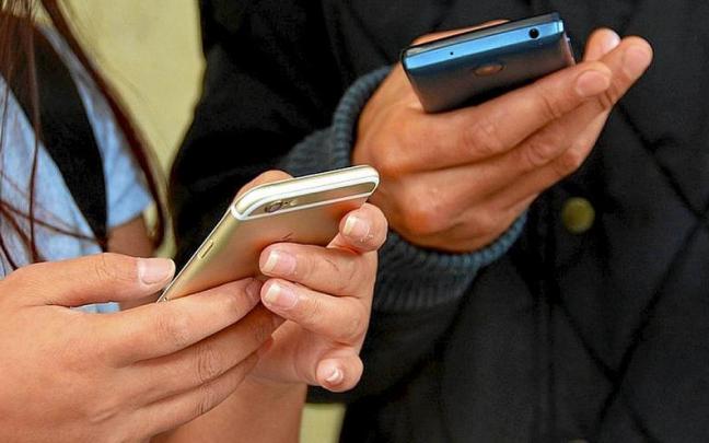 Dos personas con sus tel&eacute;fonos m&oacute;viles