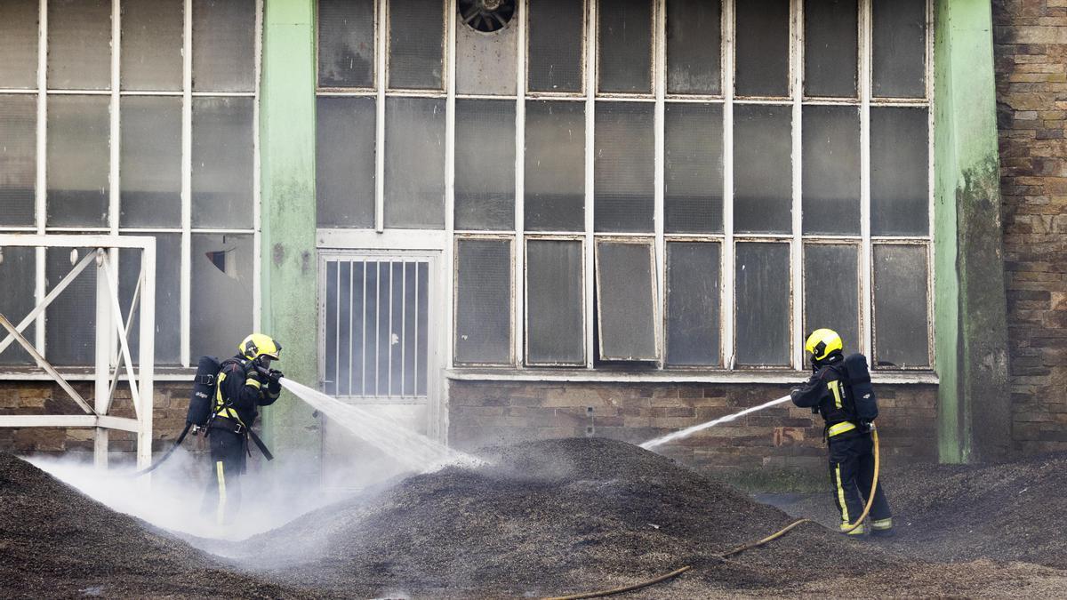 Dos bomberos trabajan en la extinción del fuego de la antigua fábrica de Pontesa en Ponte Sampaio, Pontevedra, Galicia.