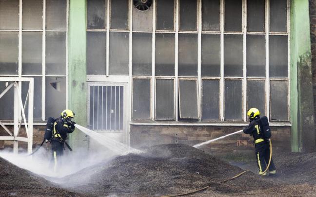Dos bomberos trabajan en la extinción del fuego de la antigua fábrica de Pontesa en Ponte Sampaio, Pontevedra, Galicia. Dos bomberos trabajan en la extinción del fuego de la antigua fábrica de Pontesa en Ponte Sampaio, Pontevedra, Galicia.