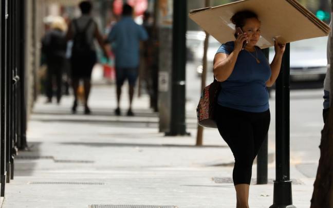 Una mujer se protege del sol con un cartón. Una mujer se protege del sol con un cartón.