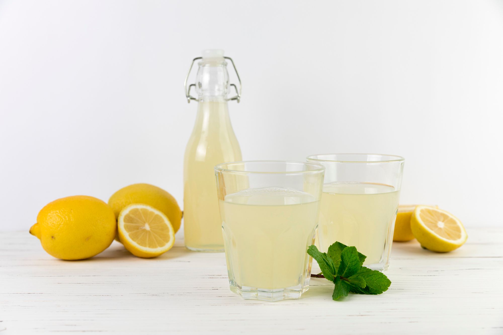 Una botella y dos vasos con limonada casera.