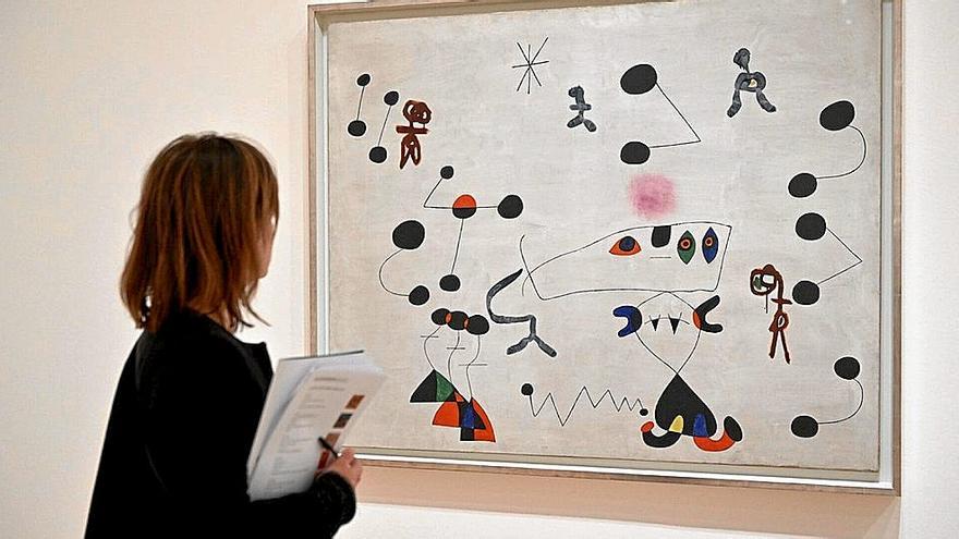 Una mujer observa uno de los cuadros de Miró en la exposición.