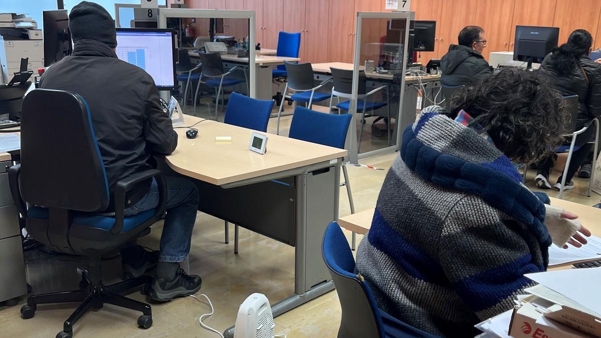 Trabajadores de la Oficina con gorro y guantes, y un calefactor en el suelo.