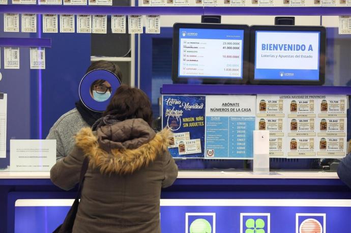 Una mujer realiza una apuesta en una administración de loterías.