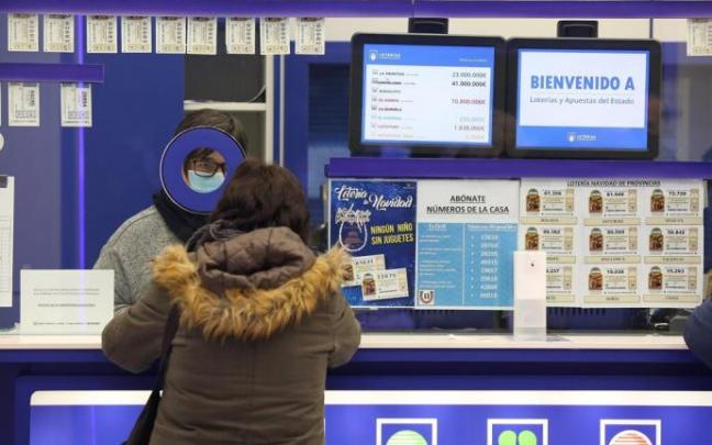 Una mujer realiza una apuesta en una administración de loterías.