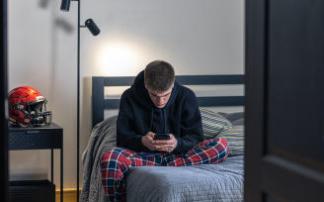 Un adolescente mira la pantalla del móvil en su habitación. Un adolescente mira la pantalla del móvil en su habitación.