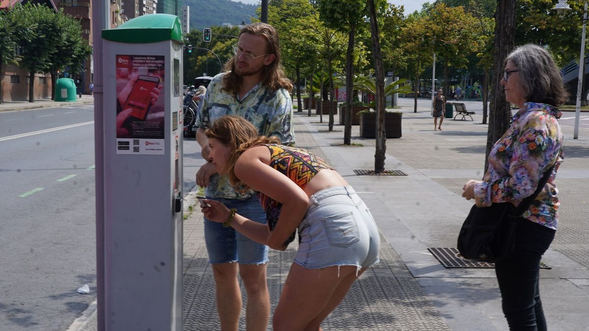 Dos jóvenes extraen este miércoles un tique en Deusto.