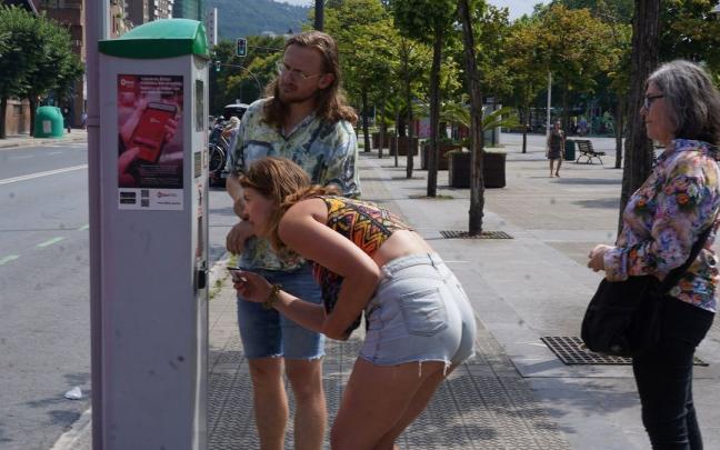 Dos jóvenes extraen este miércoles un tique en Deusto.