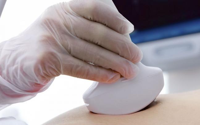 Un médico realiza una ecografía a una mujer. Un médico realiza una ecografía a una mujer.