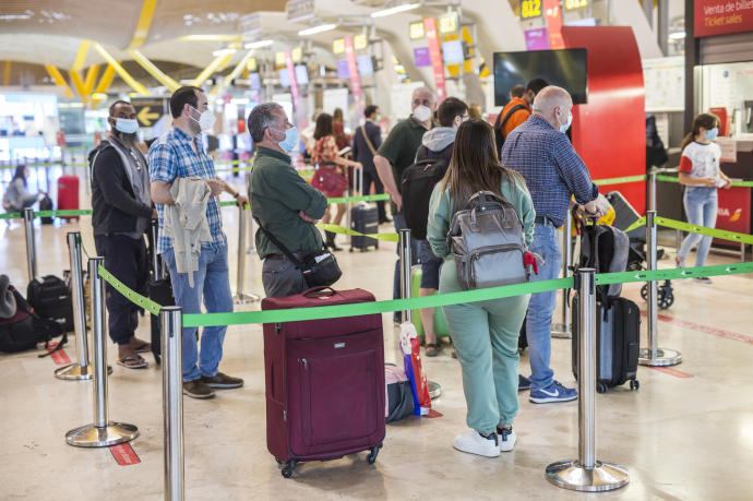 Varias personas hacen fila con maletas en la terminal T4 del Aeropuerto Adolfo Suárez Madrid-Barajas