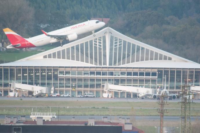 Un avión de Iberia despega con la terminal de Loiu al fondo