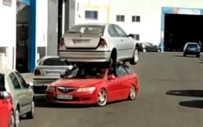 El coche, con el otro encima circulando por un pol&iacute;gono industrial.