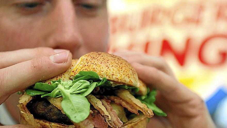 Un adolescente a punto de comerse una hamburguesa. | FOTO: E.PRESS