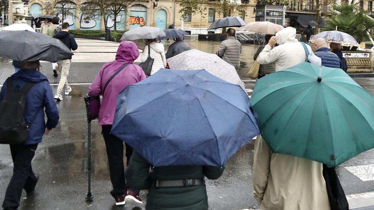 Varias personas se refugian de la lluvia en Donostia bajo los paraguas