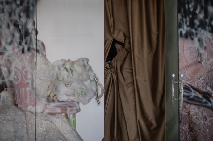El rostro de una mujer asoma tras la puerta de un antiguo salón de belleza en Kabul.