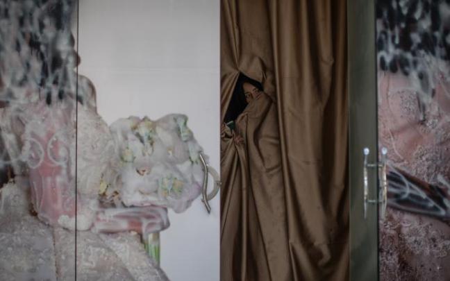 El rostro de una mujer asoma tras la puerta de un antiguo salón de belleza en Kabul. El rostro de una mujer asoma tras la puerta de un antiguo salón de belleza en Kabul.