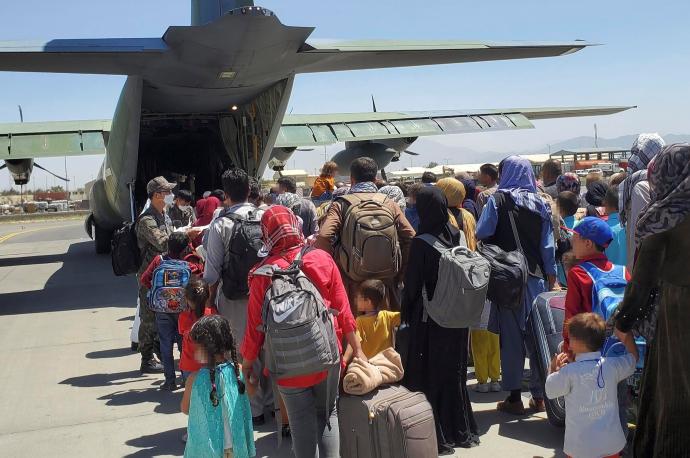 Decenas de afganos esperan a subir a un avión para ser evacuados.