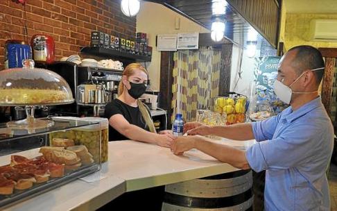 Una camarera sirve un botellín de agua a un cliente en el interior de un local hostelero. Foto: Oskar González
