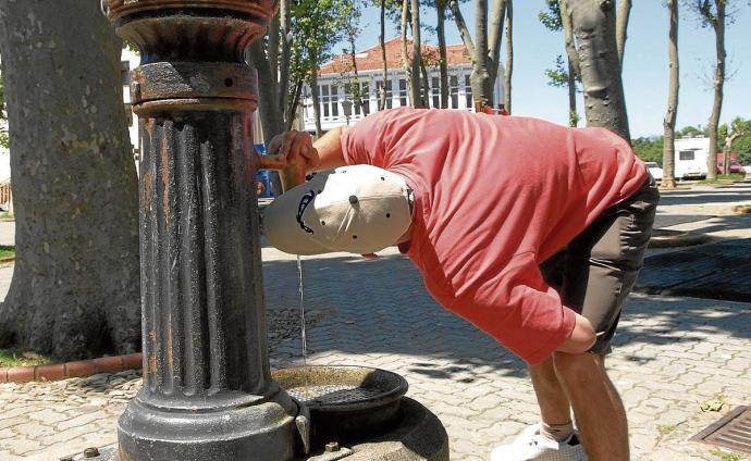 Un joven bebe agua en una fuente de Mundaka.