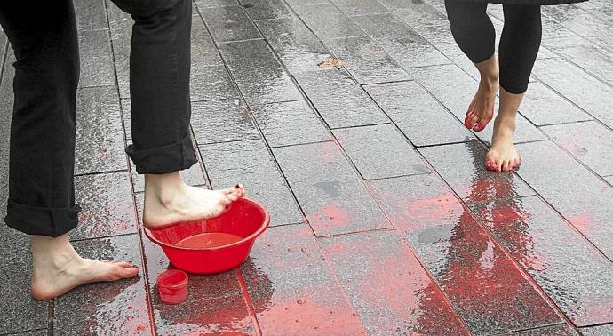 Mujeres manchan sus pies de rojo en un acto de protesta. Hoy, 25-N, día contra la violencia hacia las mujeres, sólo por el hecho de serlo, miles de personas van a salir a la calle para plantarse ante esta lacra social lejos aún de remitir, a tenor de los