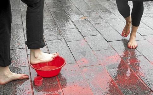 Mujeres manchan sus pies de rojo en un acto de protesta. Hoy, 25-N, día contra la violencia hacia las mujeres, sólo por el hecho de serlo, miles de personas van a salir a la calle para plantarse ante esta lacra social lejos aún de remitir, a tenor de los