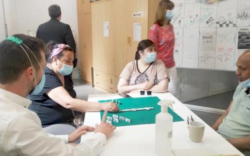 Varios usuarios del albergue esta mañana echando una partida de dominó con un trabajador social