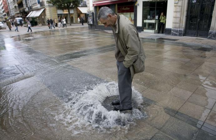 Un hombre sobre una alcantarilla de Vitoria tras un reventón, en una imagen de archivo