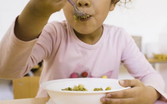 Niña comiendo en el comedor escolar.